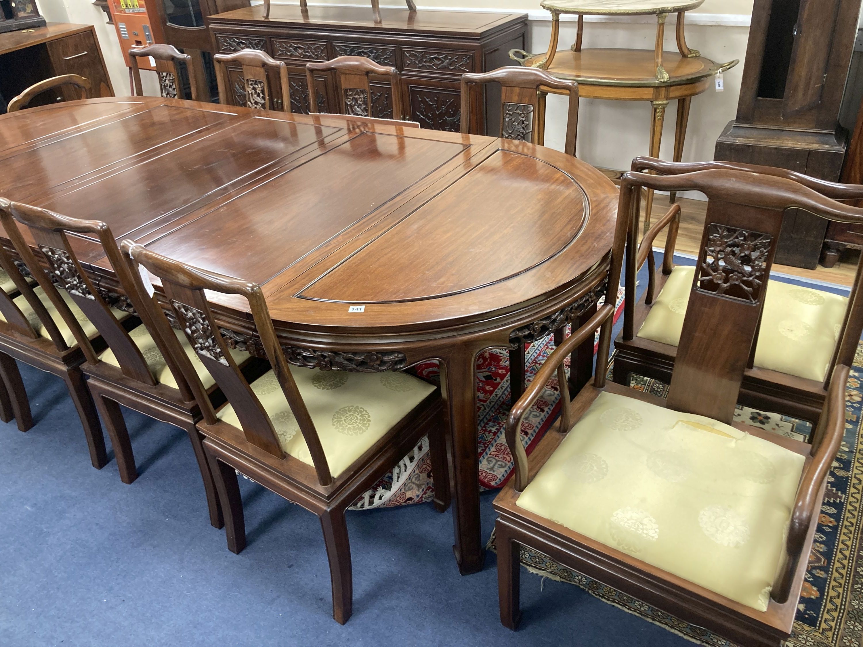 A 20th century Chinese carved hardwood dining room suite comprising sideboard fitted with four drawers above four carved panelled cupboard doors, shelved interior, raised on bracket base, length 183cm, depth 48cm height